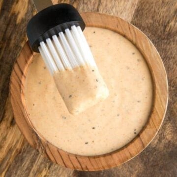 A bowl of Alabama White Sauce in a wooden bowl with a nylon brush.