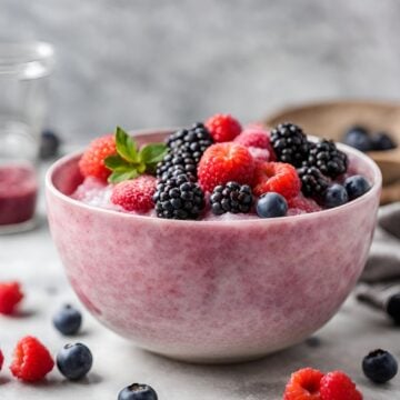 Blush colored bowl filled with blended tallow and fruit, topped with berries.