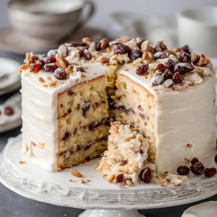 A layered cake topped with candied fruit and a few slices missing.