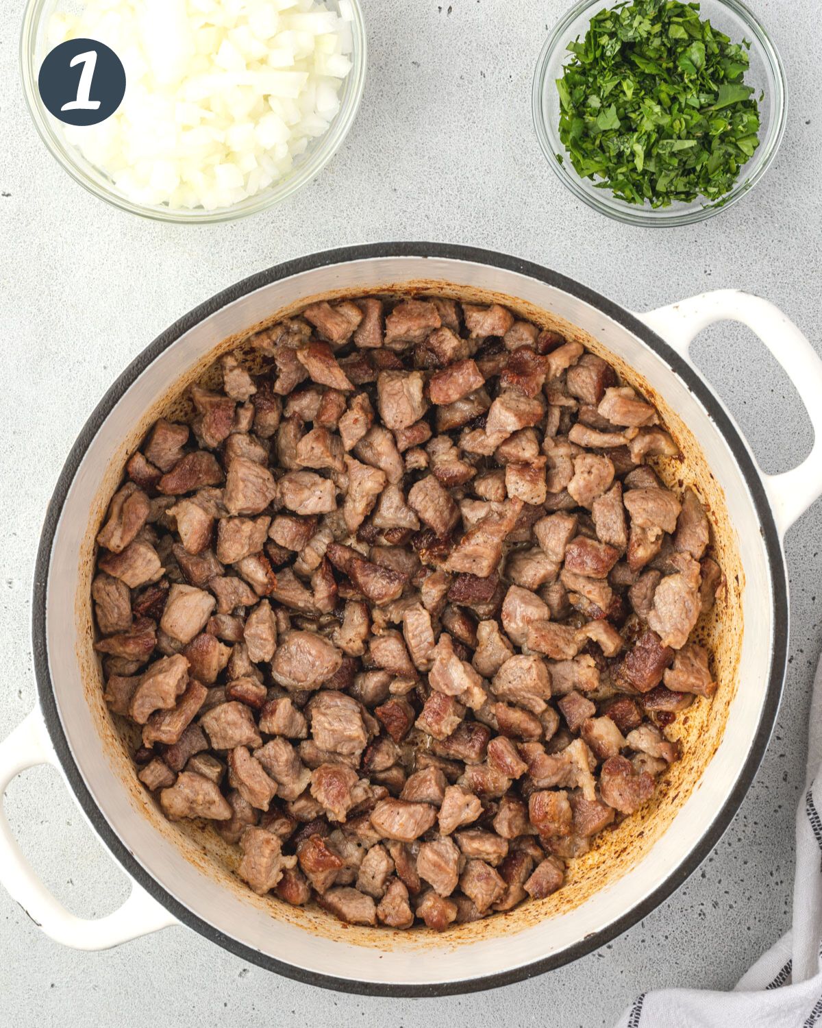 Browned pork cubes in a large pan.