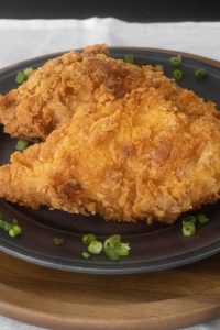 2 pieces of fried chicken on a grey plate
