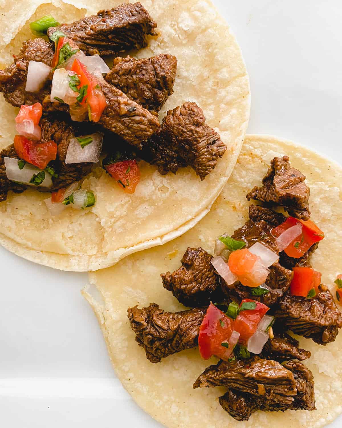 Two street tacos lying flat on a plate.