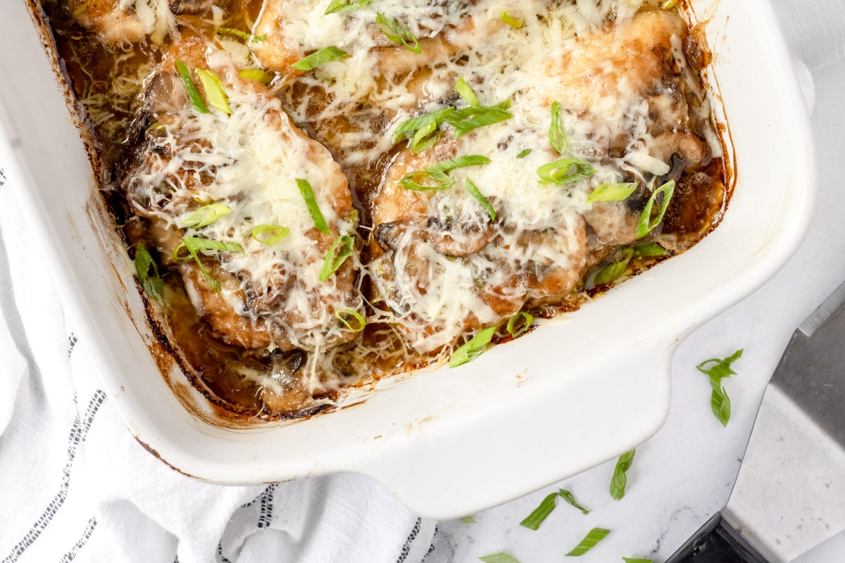 Pan of chicken with melted cheese, mushrooms, and green onions.