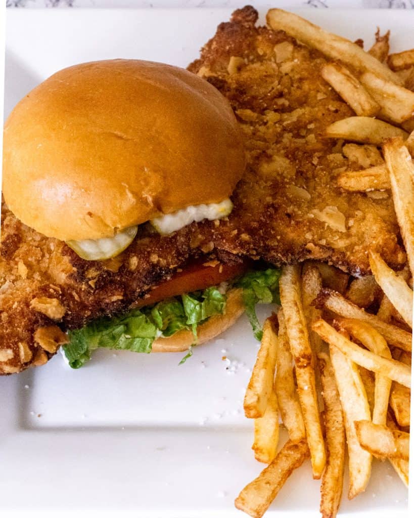 Hoosier Breaded Pork Tenderloin Sandwich on a plate with fries