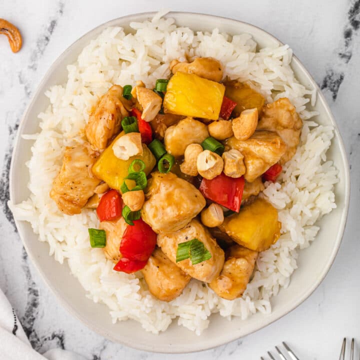 Plate of honey pineapple teriyaki chicken on rice, topped with cashews.