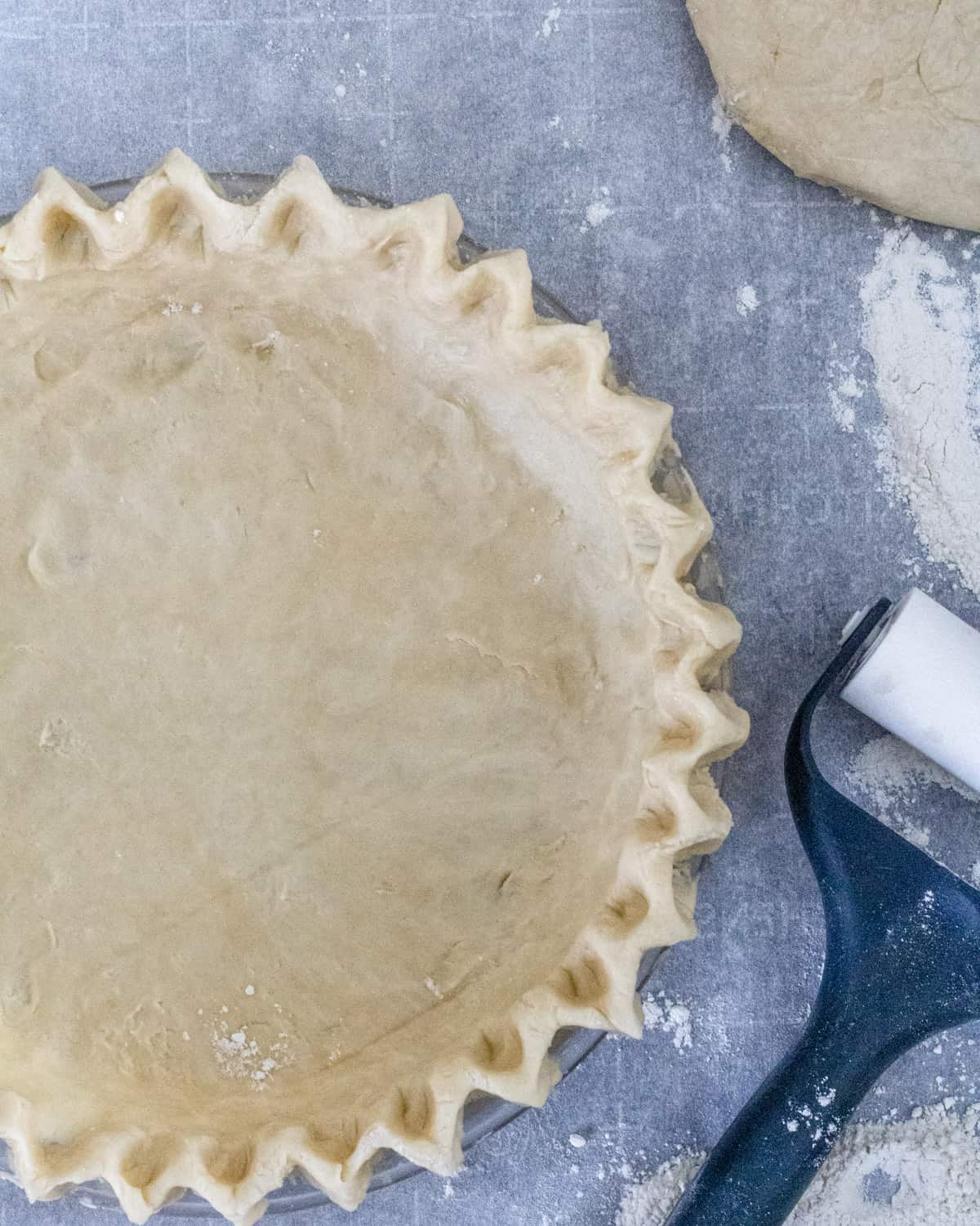 Unbaked Pie crust with dough roller in the corner.