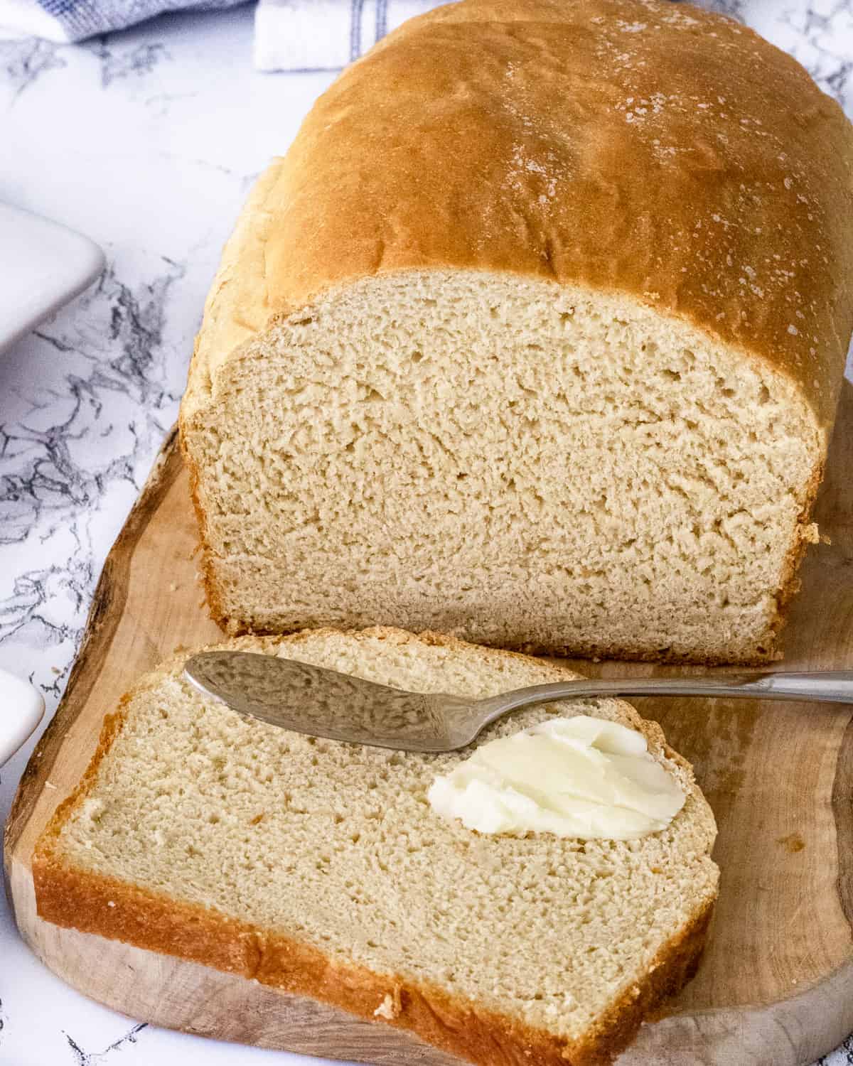 Loaf of honey wheat bread. Once slice in front with a dab of butter and a butter knife.
