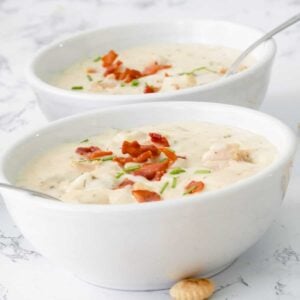 Two bowls of clam chowder, topped with bacon.