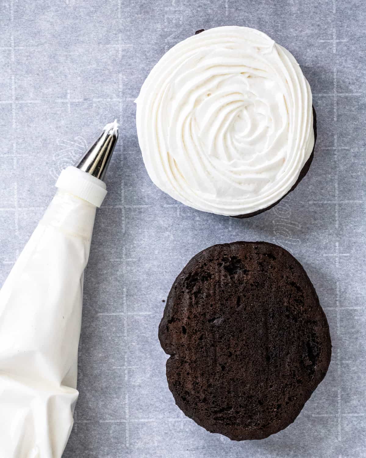 A Whoopie Pie with the top off, and a piping bag of filling next to it.