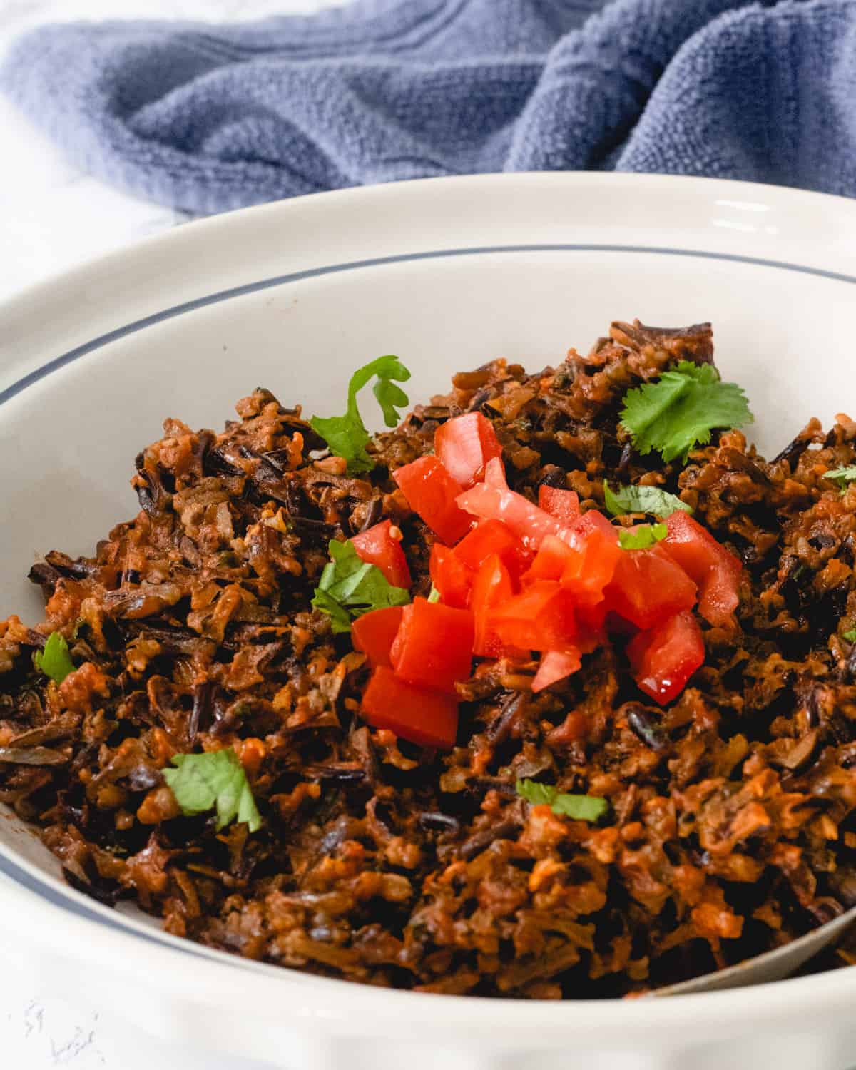 Bowl of Mexican wild rice, topped with chopped tomatoes and cilantro.