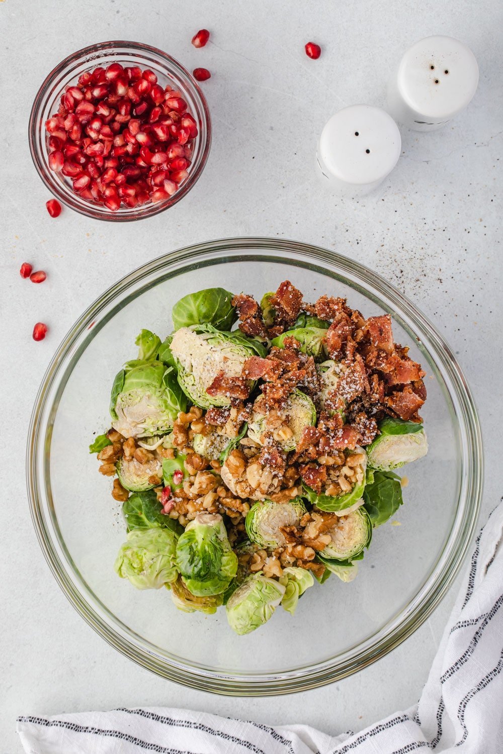 Bowl of brussels sprouts ingredients with pomegranate bowl on the side.