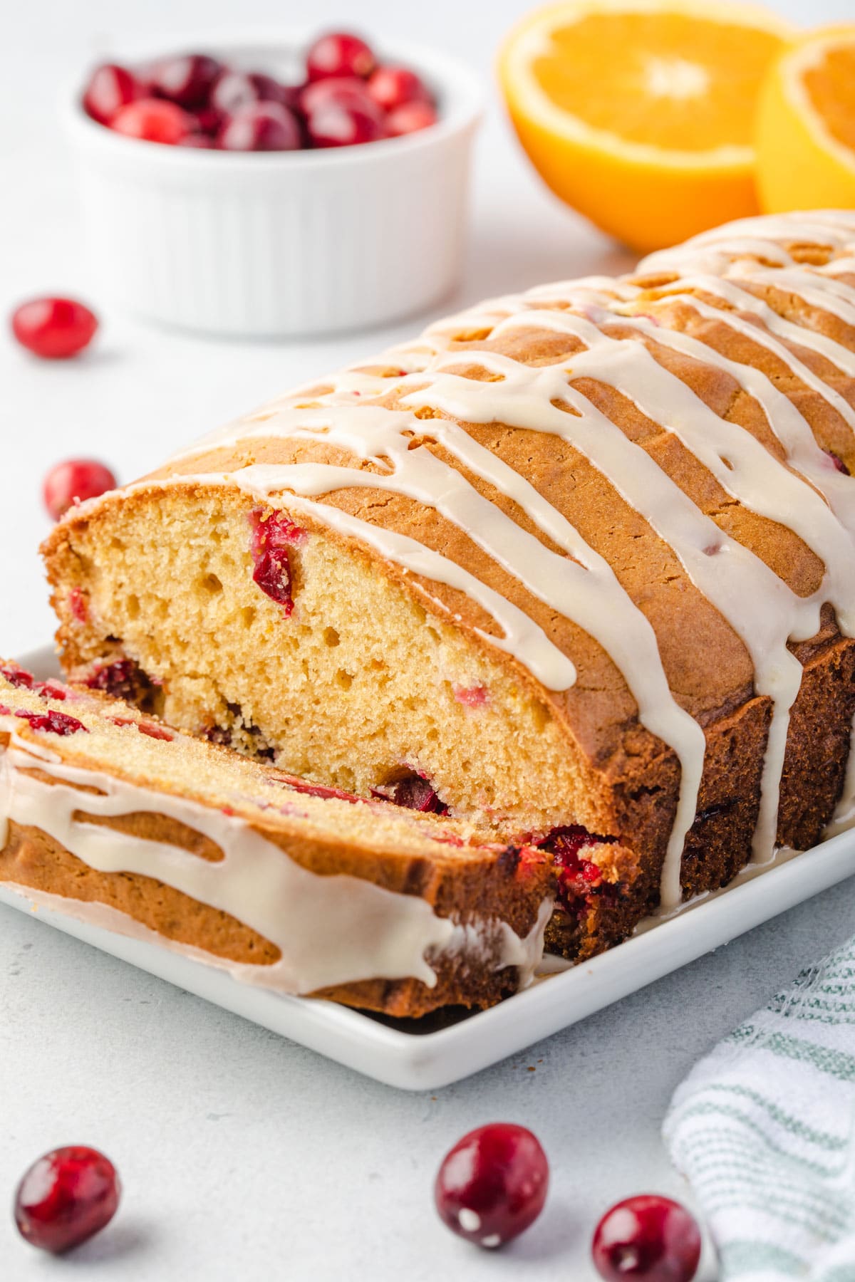 Cranberry bread on a platter with one piece sliced and angeled away from loaf.