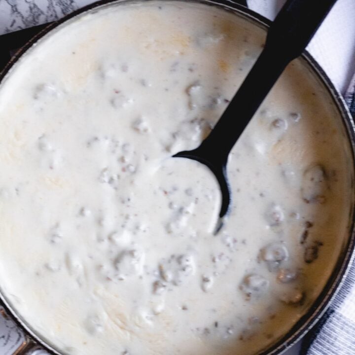 Skillet of sawmill sausage gravy with a black serving spoon.