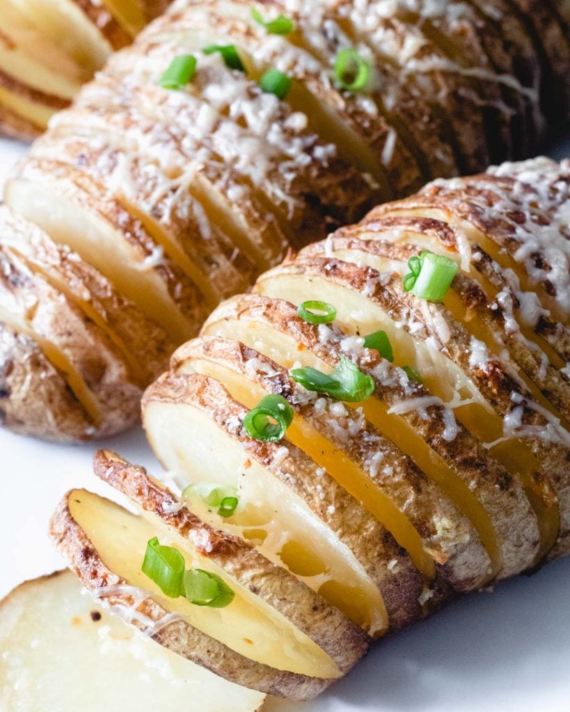 Hasselback potatoes topped with parmesan cheese and green onion