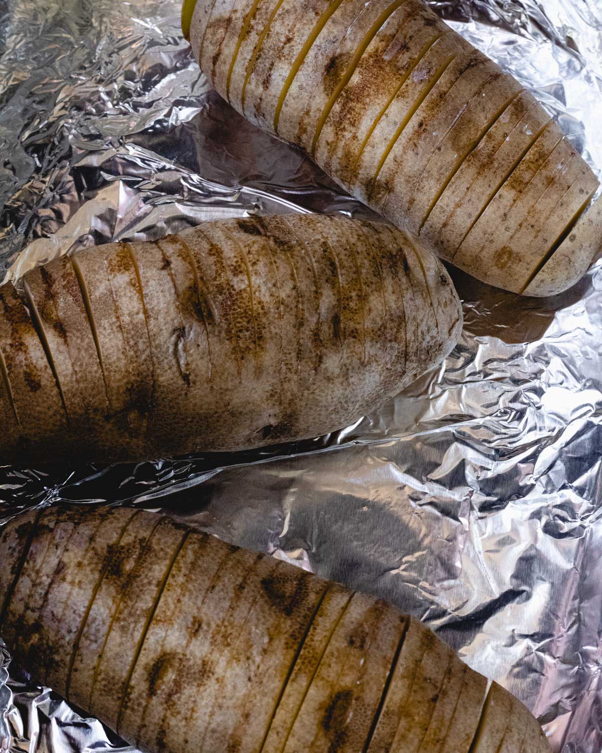 3 sliced potatoes in a foil-lined baking dish.