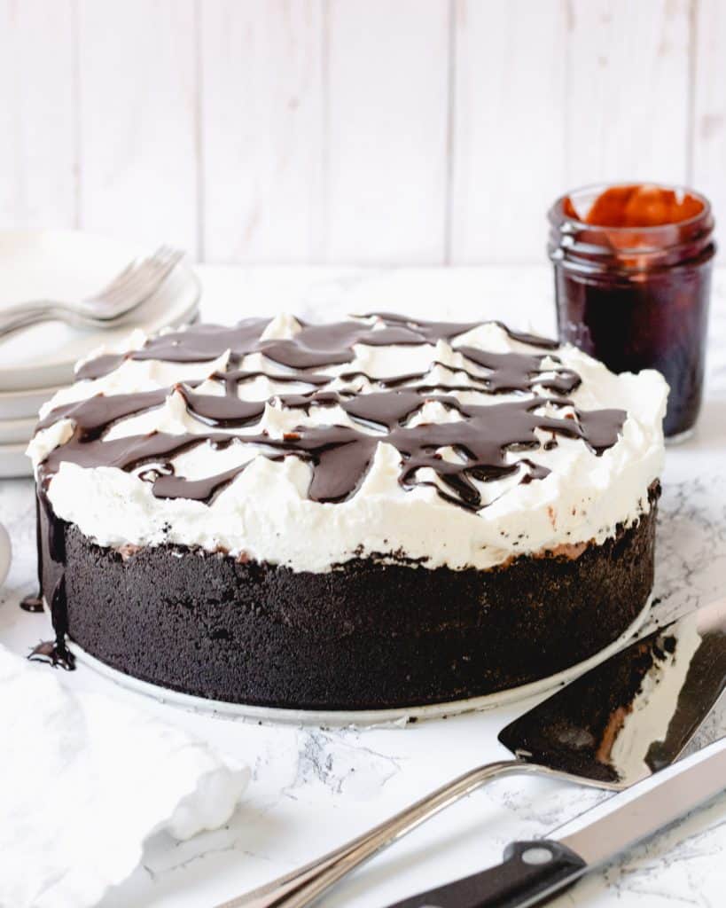 Whole Mississippi Mud Pie with cake server and knife in front, and jar of hot fudge in background.