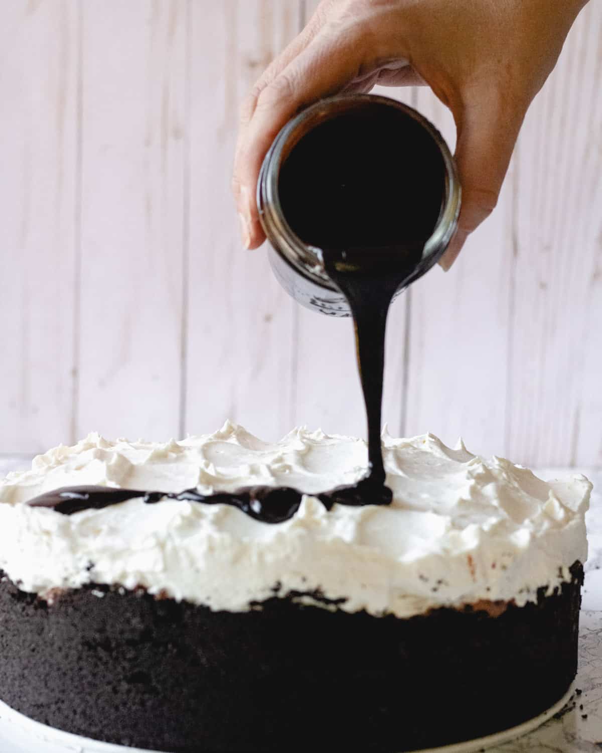 Mississippi Mud Pie with hot fudge being poured out of a jar over the top of the pie.