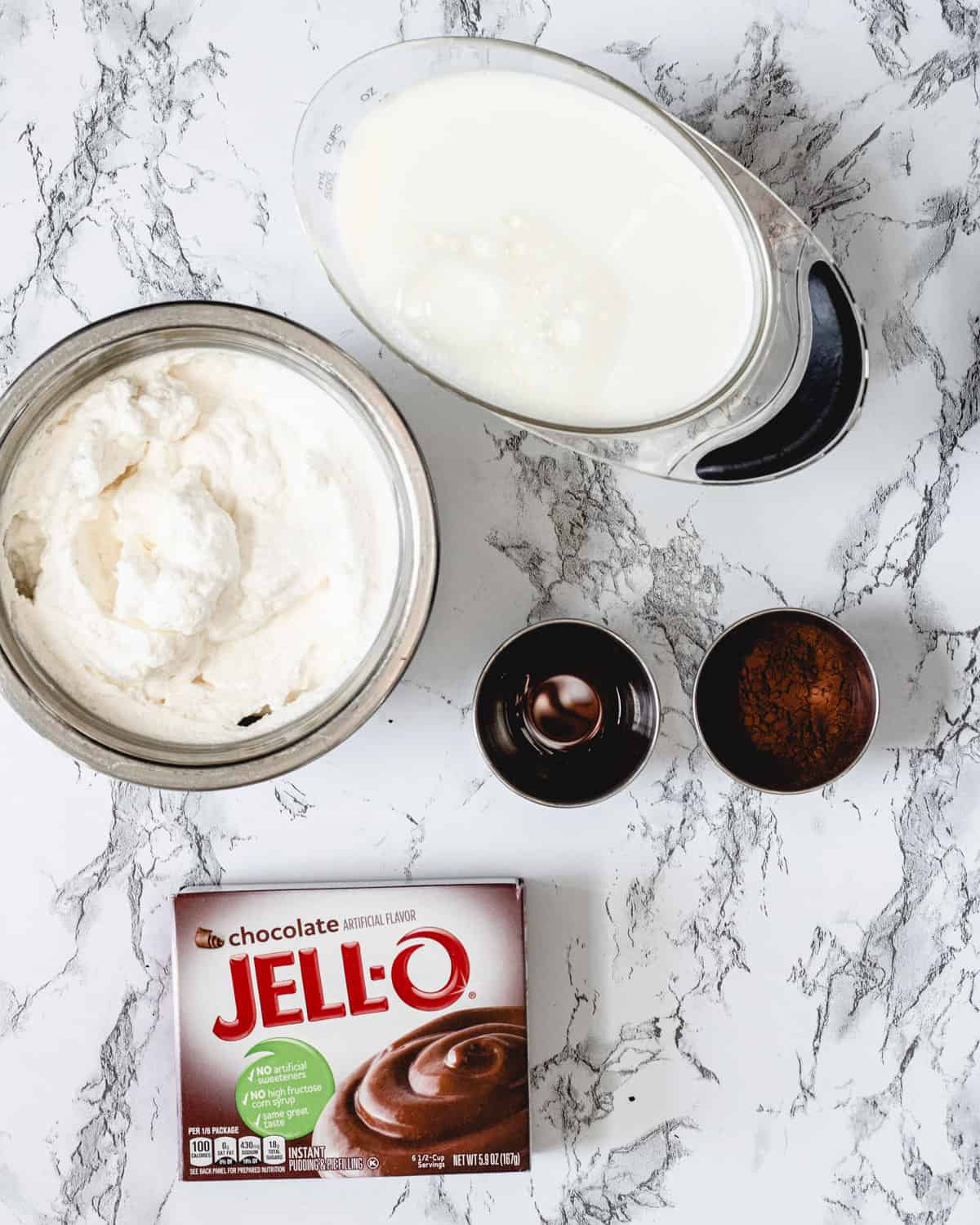 Chocolate mousse ingredients laid out on a counter, including pudding, whipped cream, milk, vanilla and Dutch-processed cocoa.