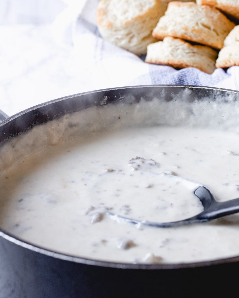 Pan of sawmill sausage gravy with basket of biscuits.