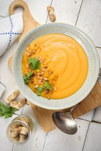 Bowl of peanut butter soup topped with peanuts and cilantro.