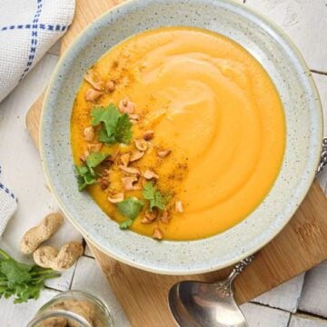 Bowl of peanut butter soup topped with peanuts and cilantro.