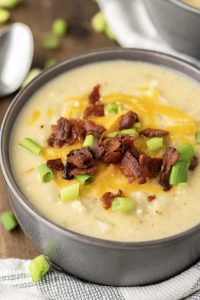 Bowl of potato soup topped with cheese, bacon, and green onions.