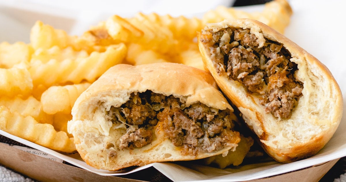 A bierock cut in half and shingled, with crinkle cut fries.