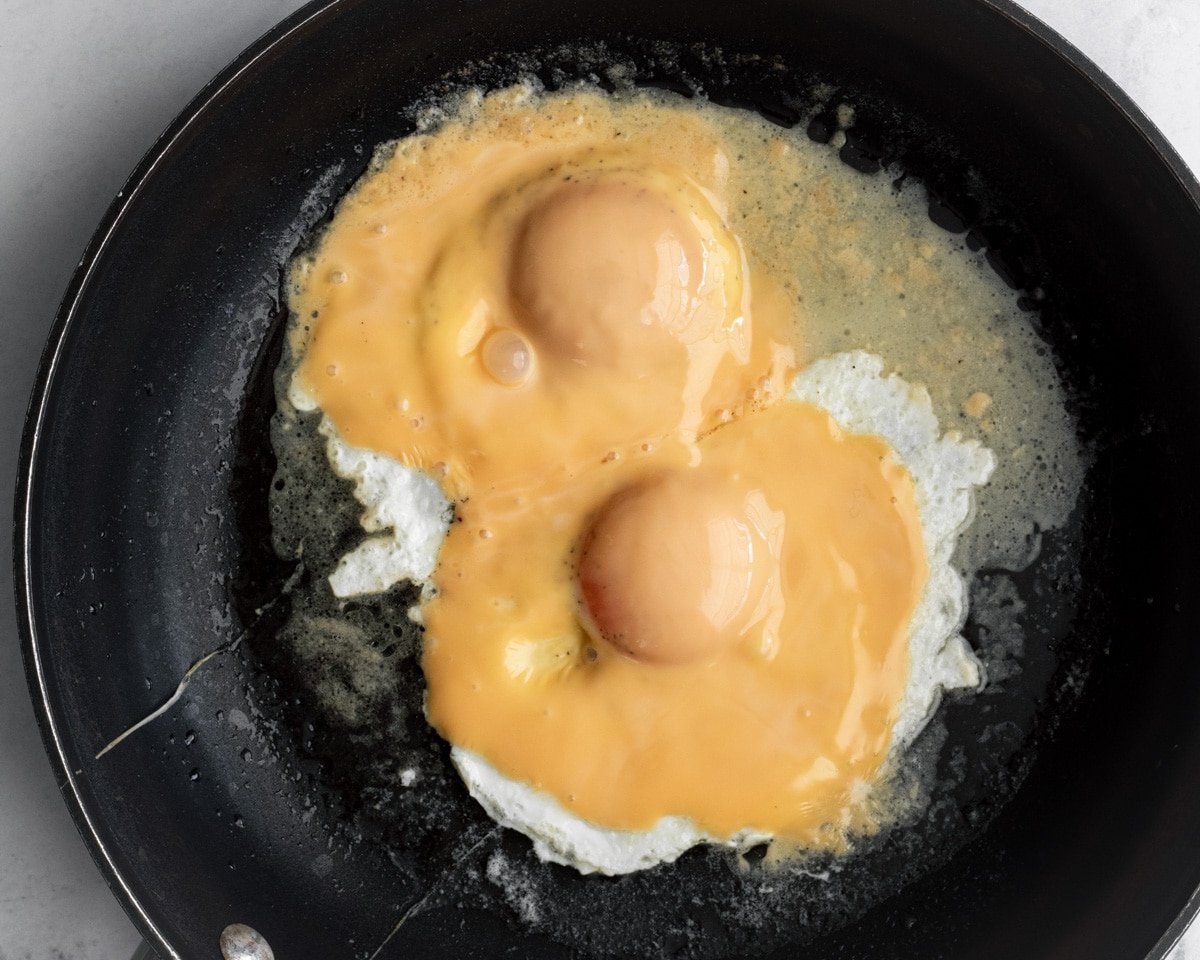 Two over easy eggs with a slice of American cheese on each.