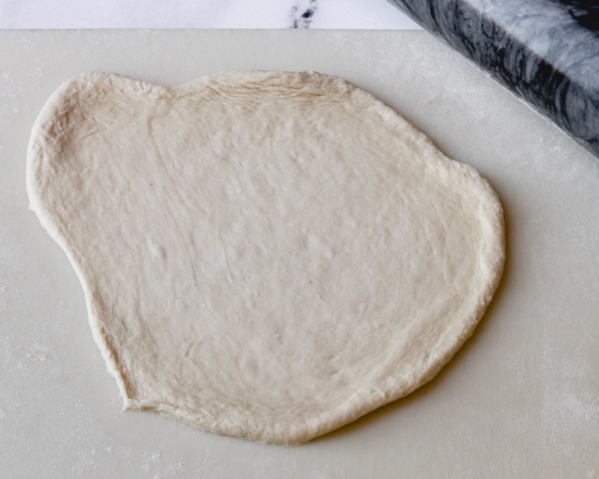 A piece of bread dough  on cutting board rolled ¼" thick.