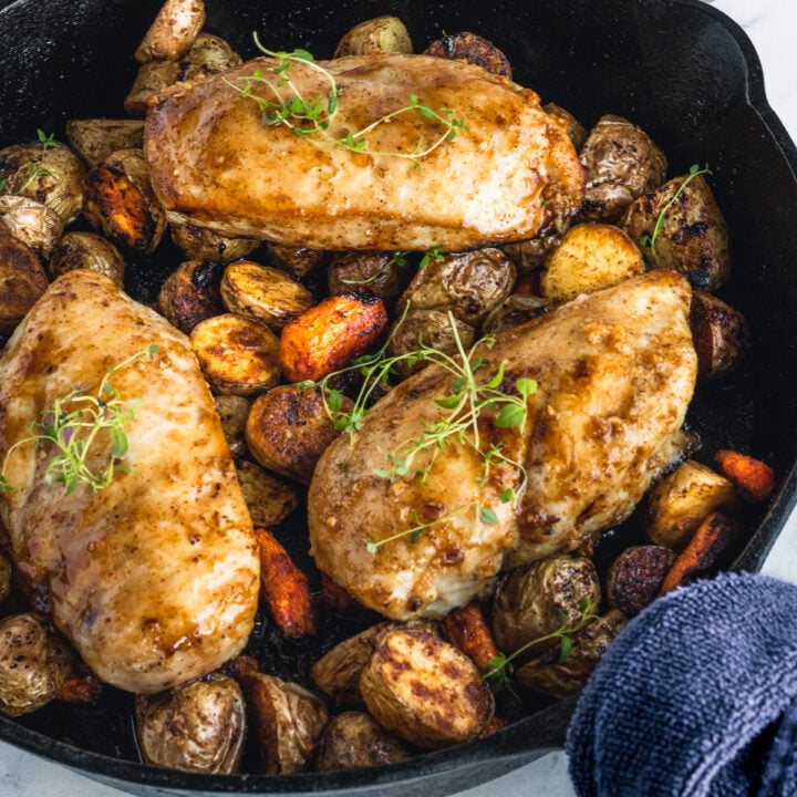 Roasted baby potatoes and carrots in a skillet topped with hot honey chicken.
