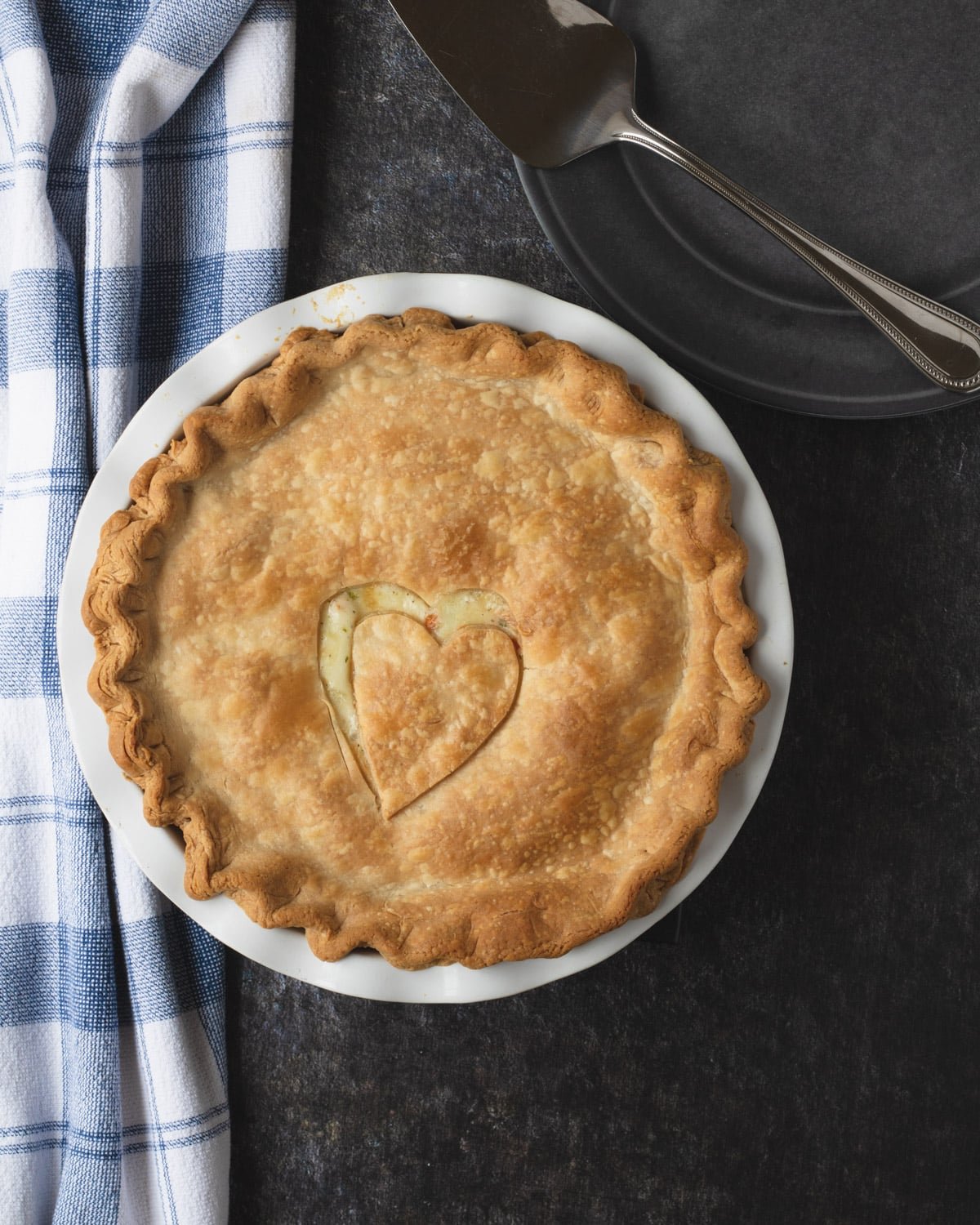 Pot pie with a heart shape cut out in the center, and the server on a plate in the top right corner, perfect for cold weather.