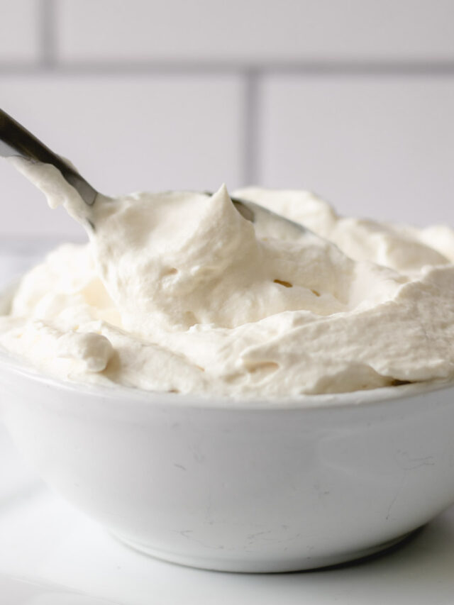 Pillowy whipped cream in a bowl with a spoon.