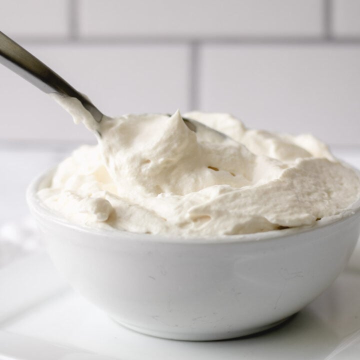 Pillowy whipped cream in a bowl with a spoon.