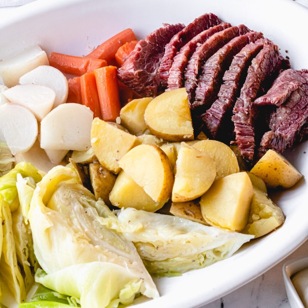 Corned beef on a platter with boiled cabbage, carrots, potatoes, and turnips.