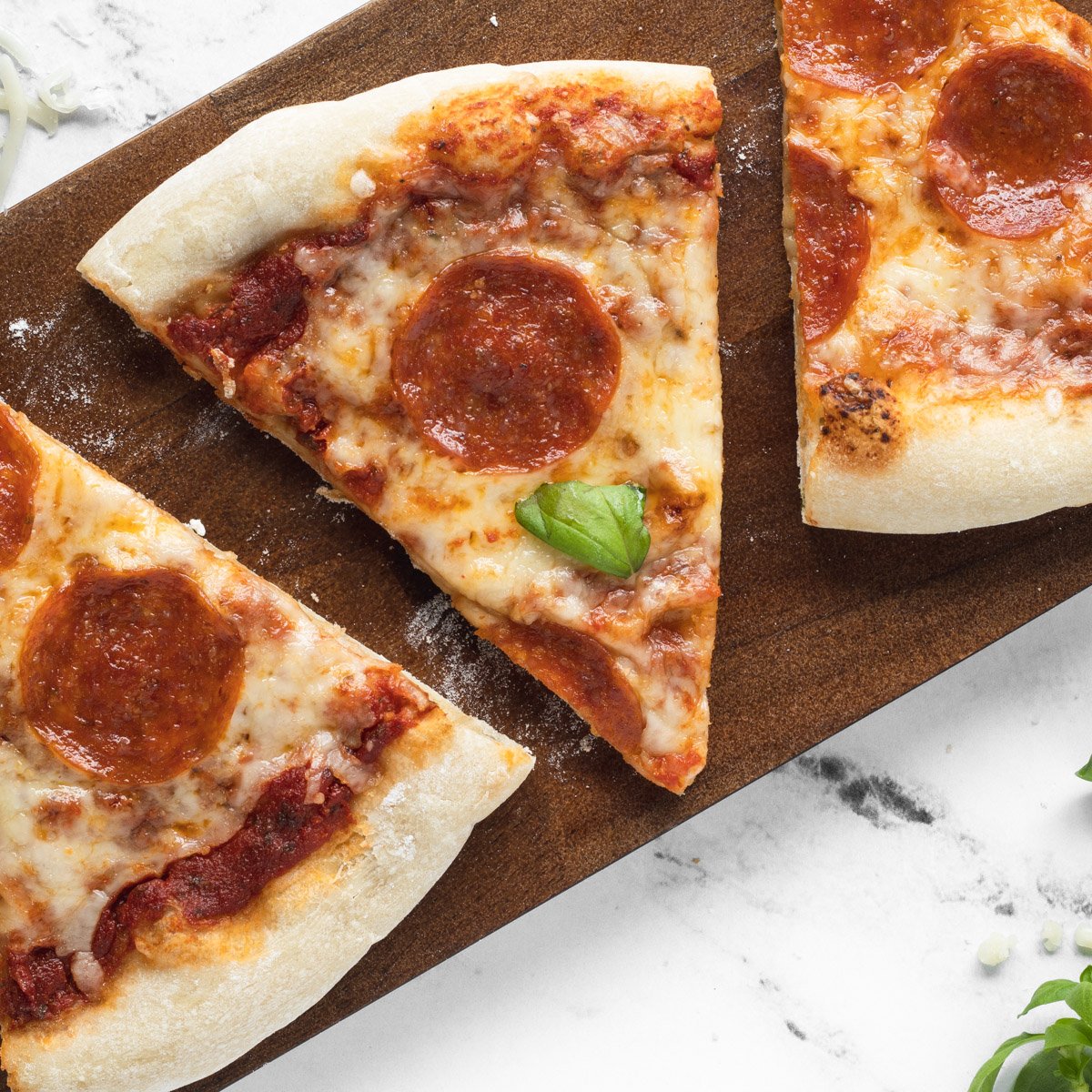 Close up of pepperoni pizza slices on a wooden board.