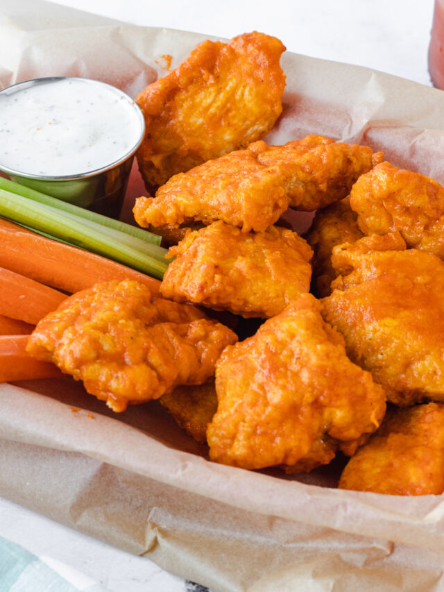 Basket of air fryer boneless chicken wings with ranch dip, carrots, and celery.