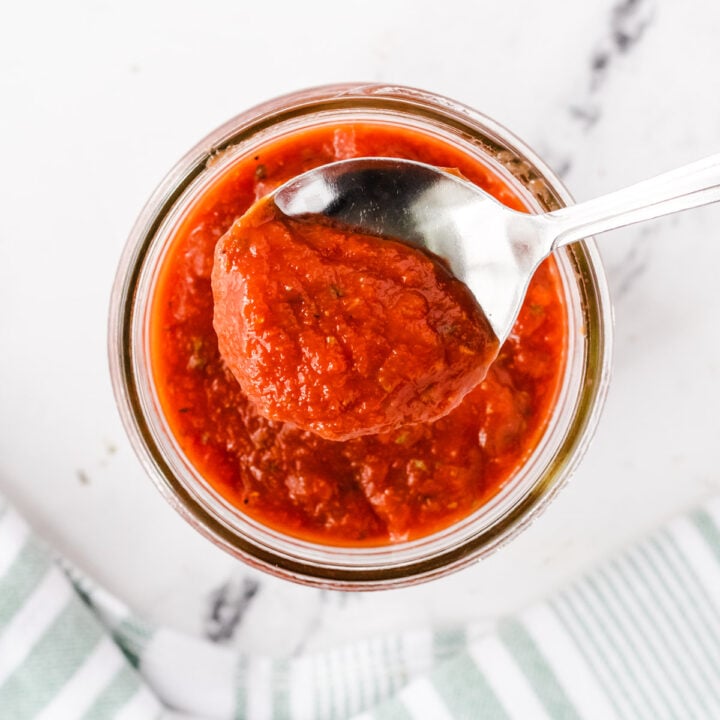 Scooping out some pizza sauce with a spoon.