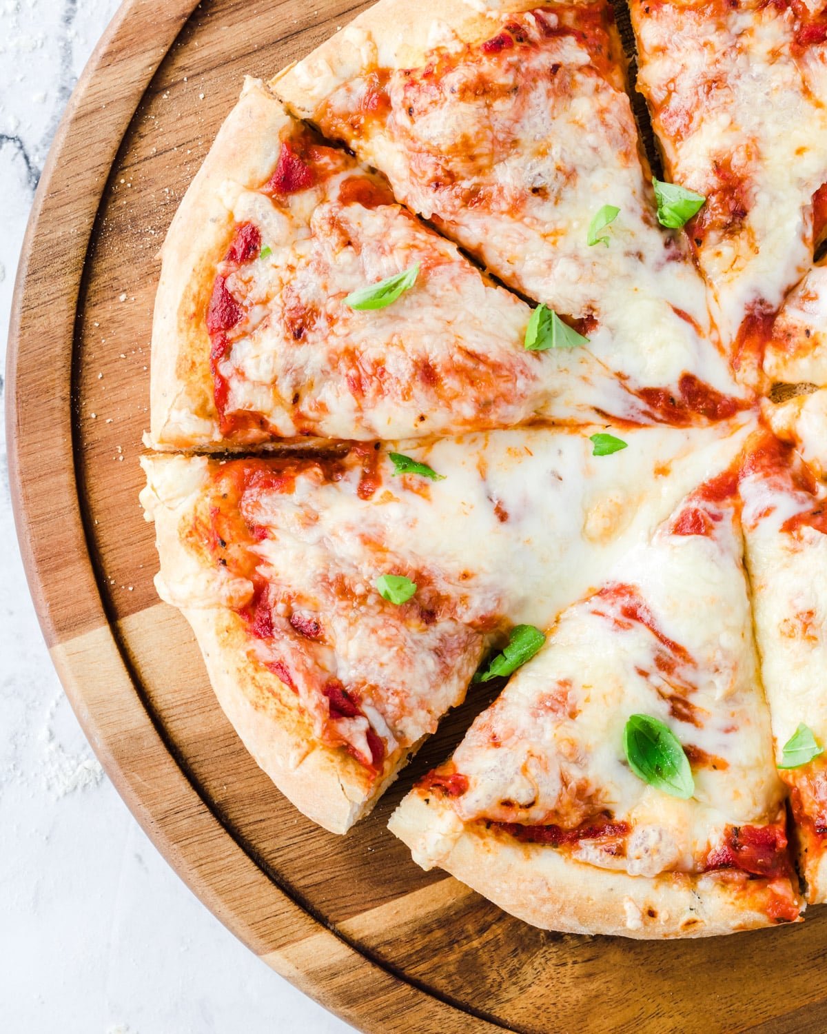 Overhead shot of sliced pizza with basil sprinkled on it.