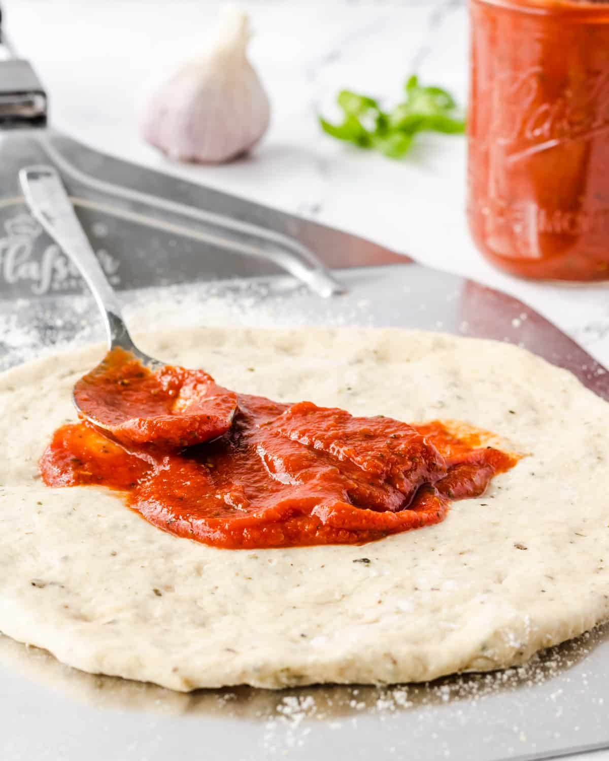 Spreadig pizza onto dough that is on a pizza peel.