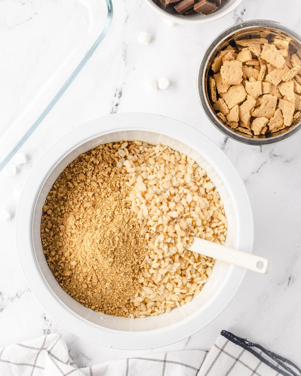 Large bowl with rice krispies and graham craker crumbs, and a spatula.