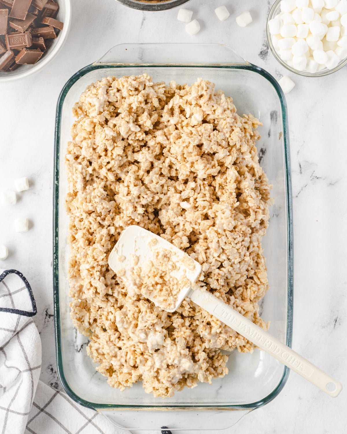 Spatula laying on top of rice krispie treats in a 9x13 pan.