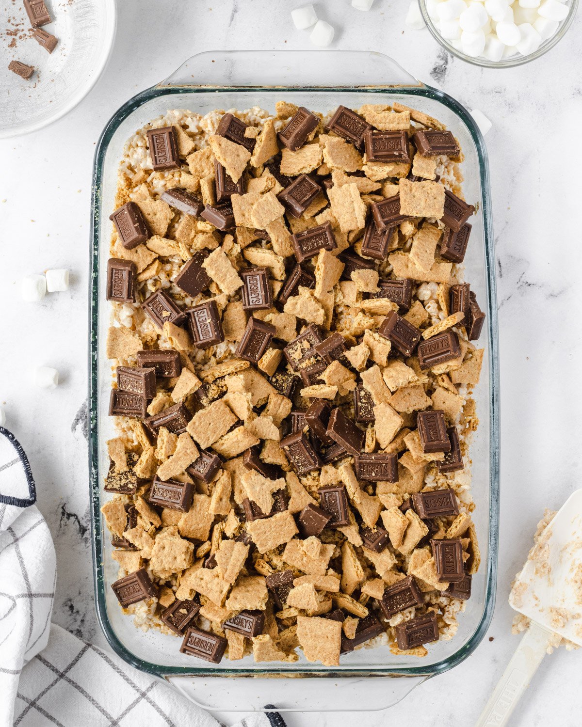 Pan of rice krispie treats topped with graham cracker pieces and chocolate.