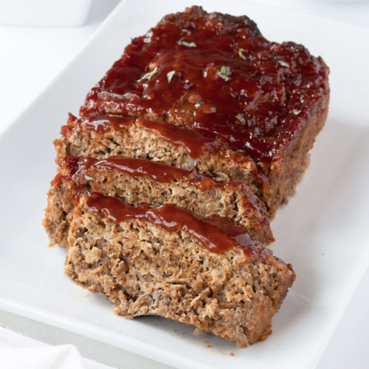 Meatloaf topped with sauce on a white plate.
