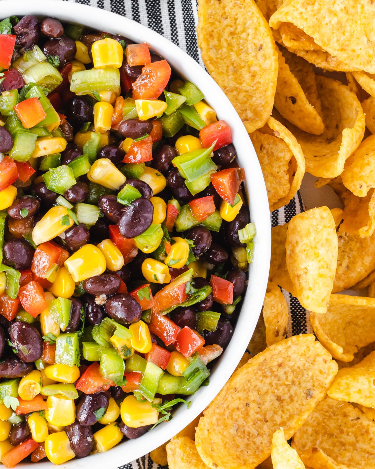 Close up of a bowl of southwest salsa with Fritos corn chip scoops on the side.