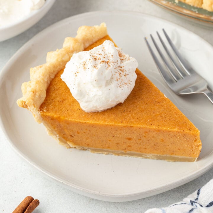 Slice of sweet potato pie made with condensed milk on a white plate and topped with whipped cream.