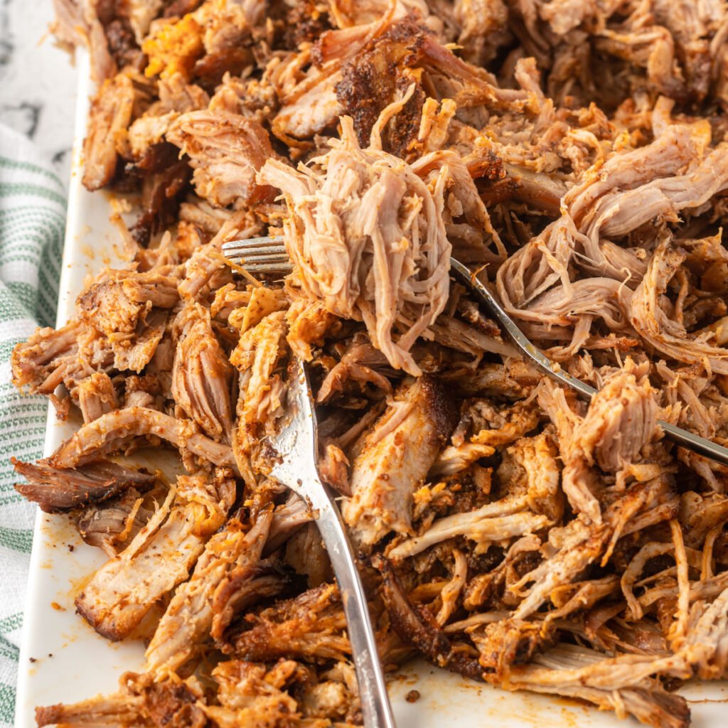 Pork shredded on a plate with two forks.