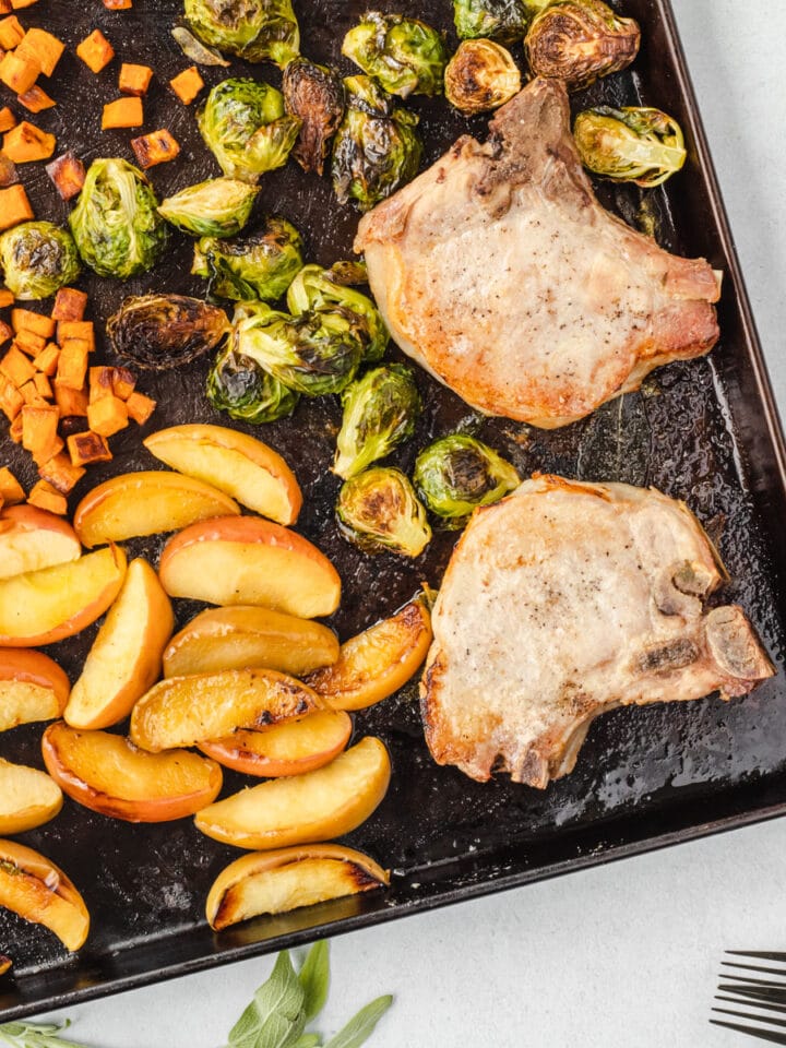 Sheet pan angled with roasted dinner on it, and sage leaves framing the pan.