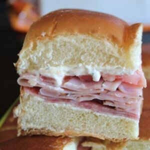 Side view of Hawaiian roll filled with crema cheese, ham, and salami.