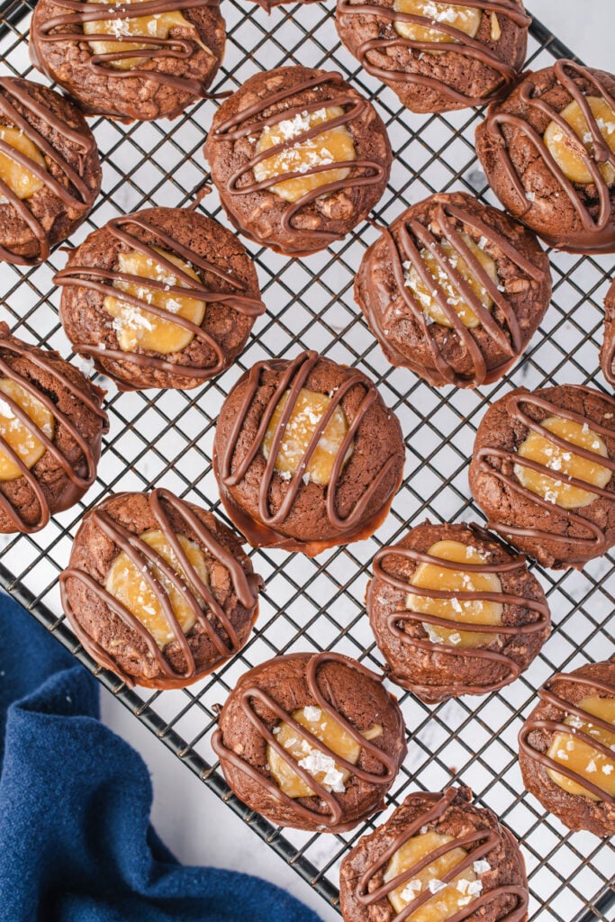 Rows of Adventurfuls cookies with chocolate drizzle, on a cooling rack.