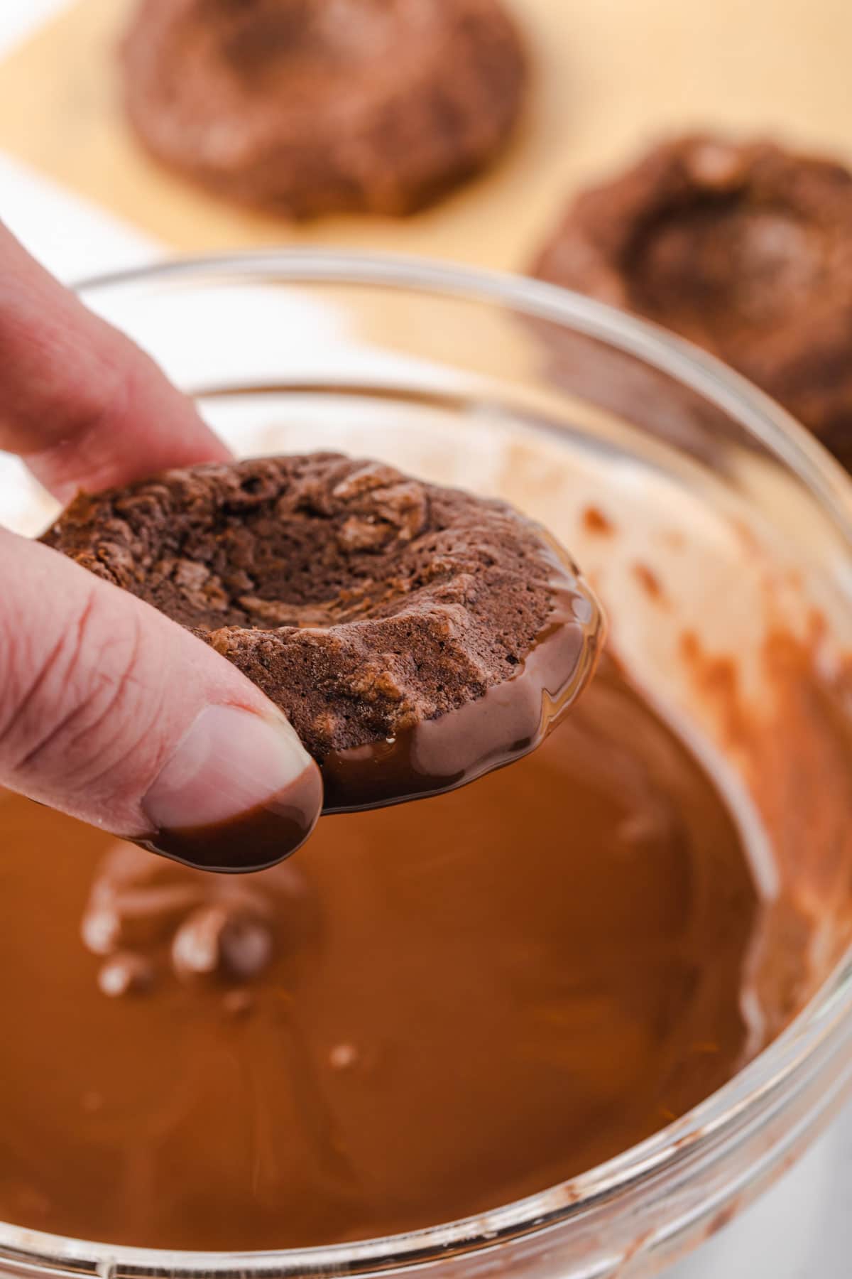 Dipping cookie into melted chocolate.